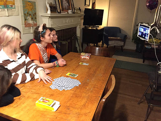Teenage girls watching virtual tarot reading on computer screen.