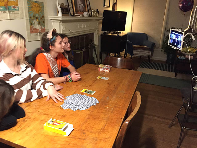Teenage girls watching virtual tarot reading on computer screen.
